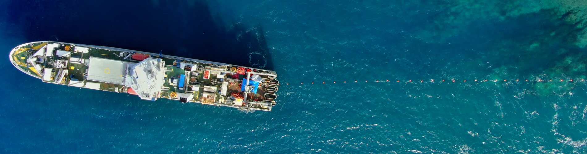 Cable ship laying submarine cable through the reef pass